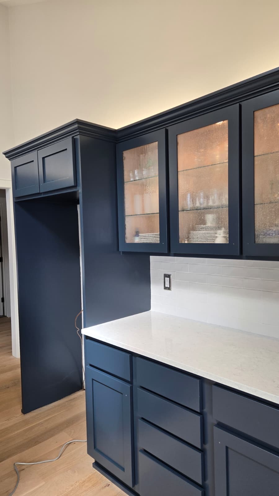 Navy blue painted kitchen cabinets with glass doors and white countertop