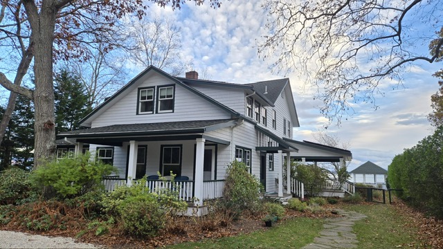 Classic white colonial home exterior with dark trim and wraparound porch